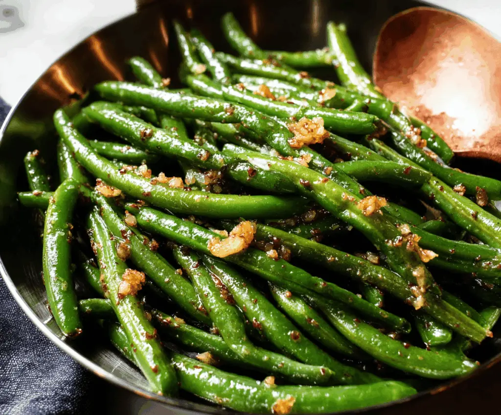 Delicious garlic butter green beans garnished with fresh herbs on a white plate