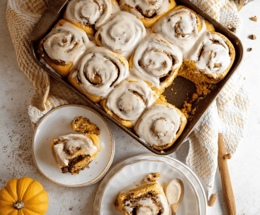 Pumpkin Cinnamon Rolls topped with Maple Frosting and served with a cup of coffee, perfect for fall mornings