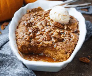 Delicious pumpkin pecan cobbler topped with whipped cream and caramel drizzle, served in a rustic baking dish.