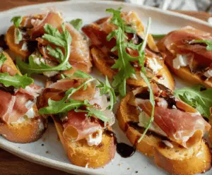 Delicious Brie and Prosciutto Crostini topped with fresh herbs on a rustic wooden platter.
