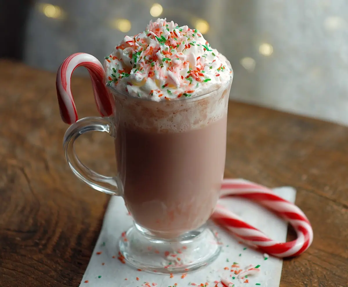 A cozy mug of Candy Cane Hot Chocolate topped with whipped cream and crushed peppermint candy.