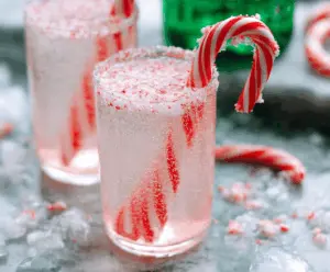 Refreshing Candy Cane Spritzer Cocktail garnished with candy canes and mint leaves in a festive glass.