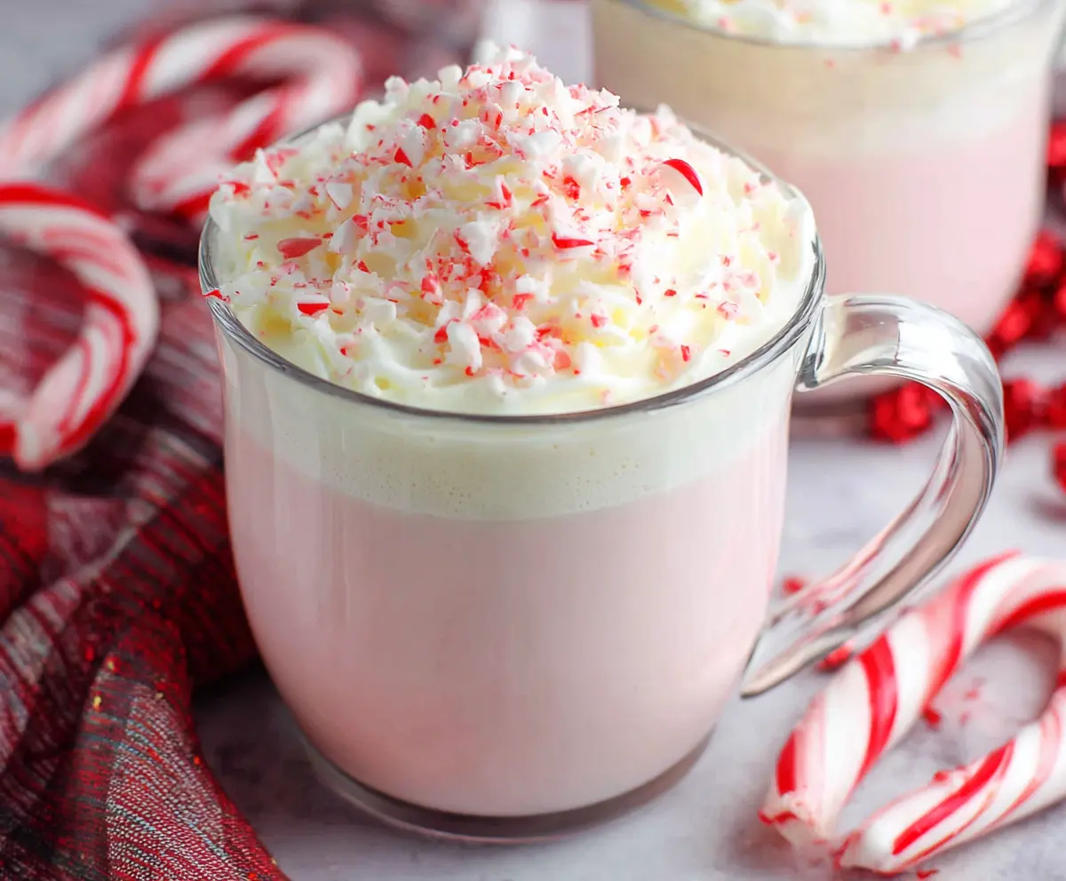 Delicious Crockpot Candy Cane White Hot Chocolate topped with whipped cream and peppermint candies
