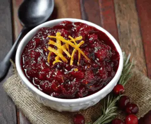 Orange Amaretto Cranberry Sauce served in a glass bowl with fresh cranberries and orange slices for a festive holiday presentation
