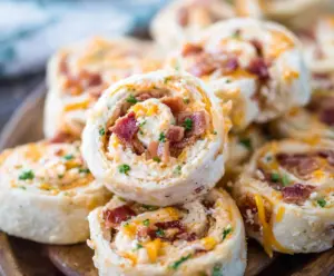 Delicious Bacon Cheddar Ranch Pinwheels on a platter, showcasing crispy bacon, melted cheddar, and fresh herbs.
