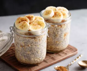 Creamy banana cinnamon overnight oats in a glass jar with fresh bananas and cinnamon sticks
