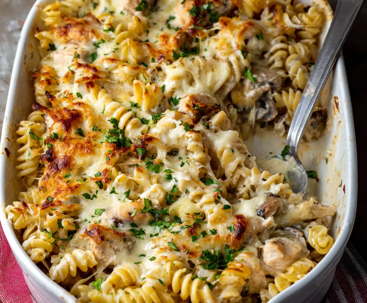 Delicious Creamy Chicken Alfredo Pasta Bake garnished with herbs on a plate.