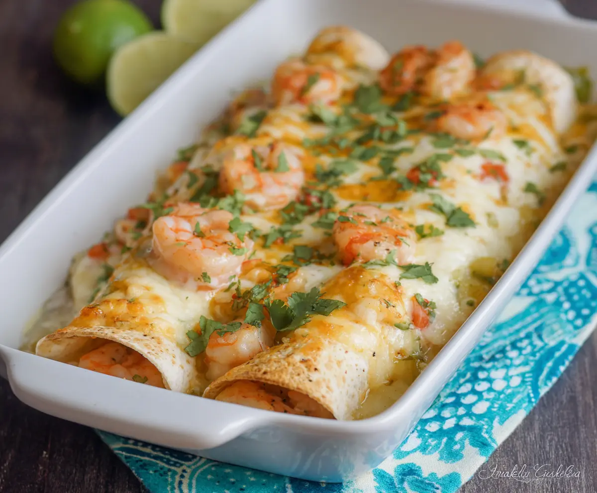 Creamy shrimp enchiladas topped with melted cheese and fresh cilantro on a white plate.