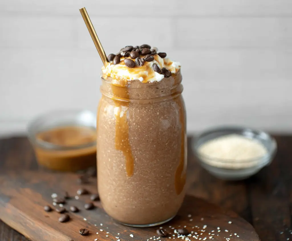 Refreshing iced coffee protein shake in a glass with ice cubes and whipped cream, perfect for a healthy snack.