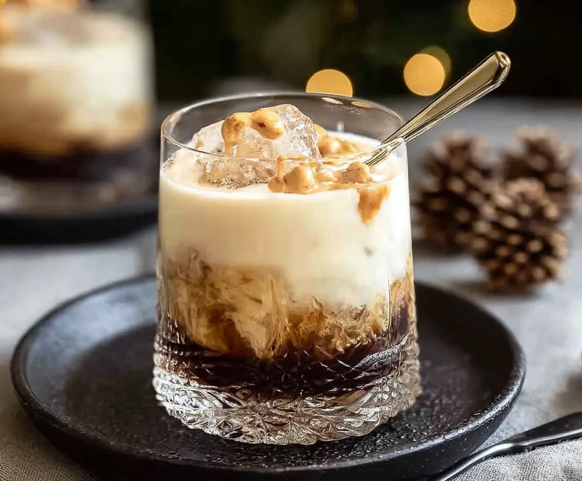 Delicious Peanut Butter White Russian Christmas Cocktail in a festive glass with a candy cane garnish.
