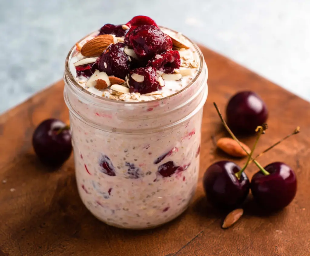 Delicious Cherry Overnight Oats topped with fresh cherries and creamy yogurt in a glass jar.
