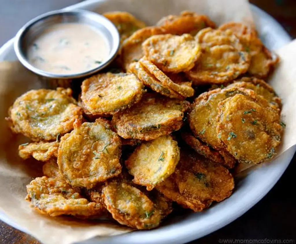 Crispy fried pickles served with dipping sauce on a rustic plate