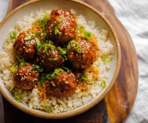 Delicious honey sriracha meatballs served on a plate garnished with fresh herbs.