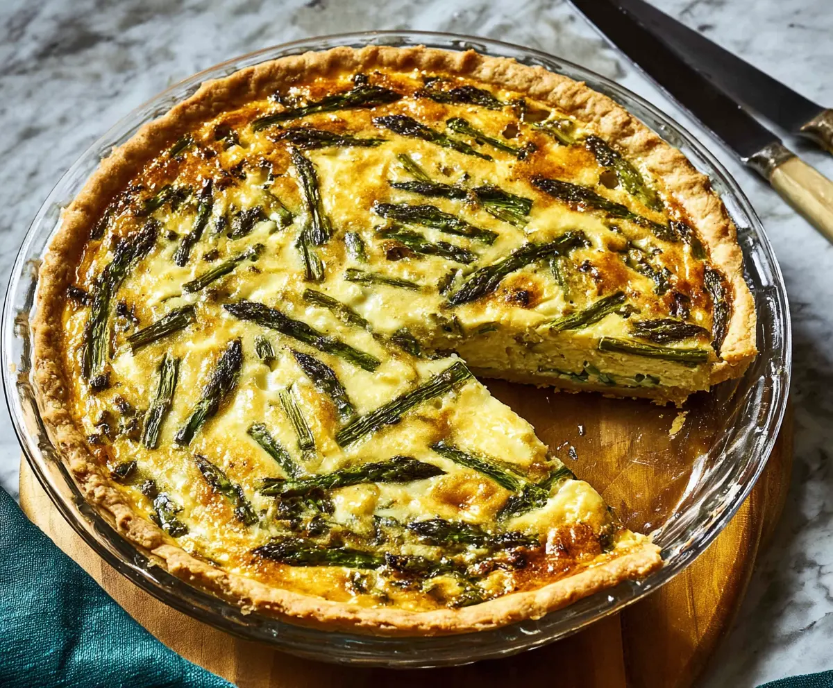Delicious asparagus and Gruyere cheese quiche on a rustic plate, perfect for brunch or lunch.