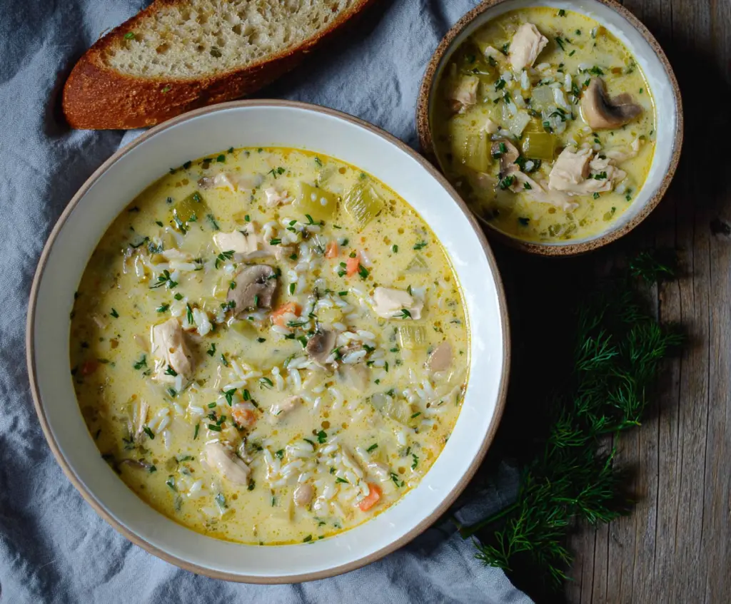 Creamy leek, chicken, and rice soup in a bowl with fresh herbs on top.