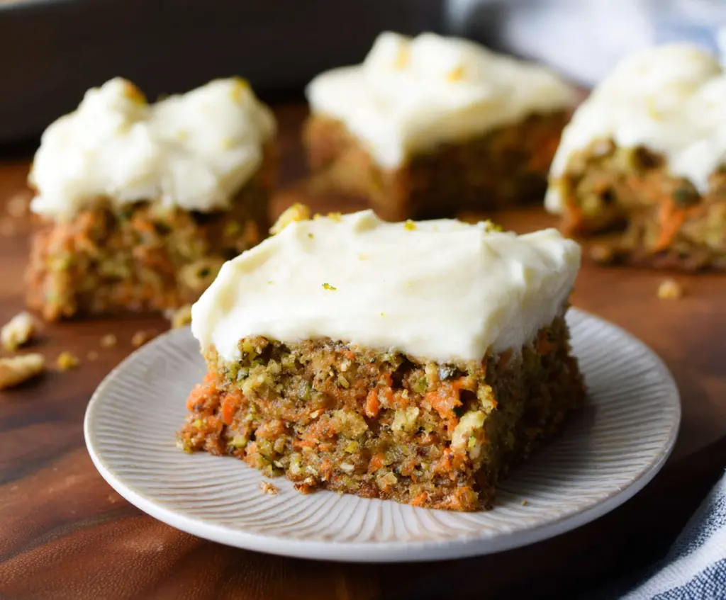 Homemade carrot and zucchini bars topped with citrus cream cheese frosting, perfect for a healthy dessert.