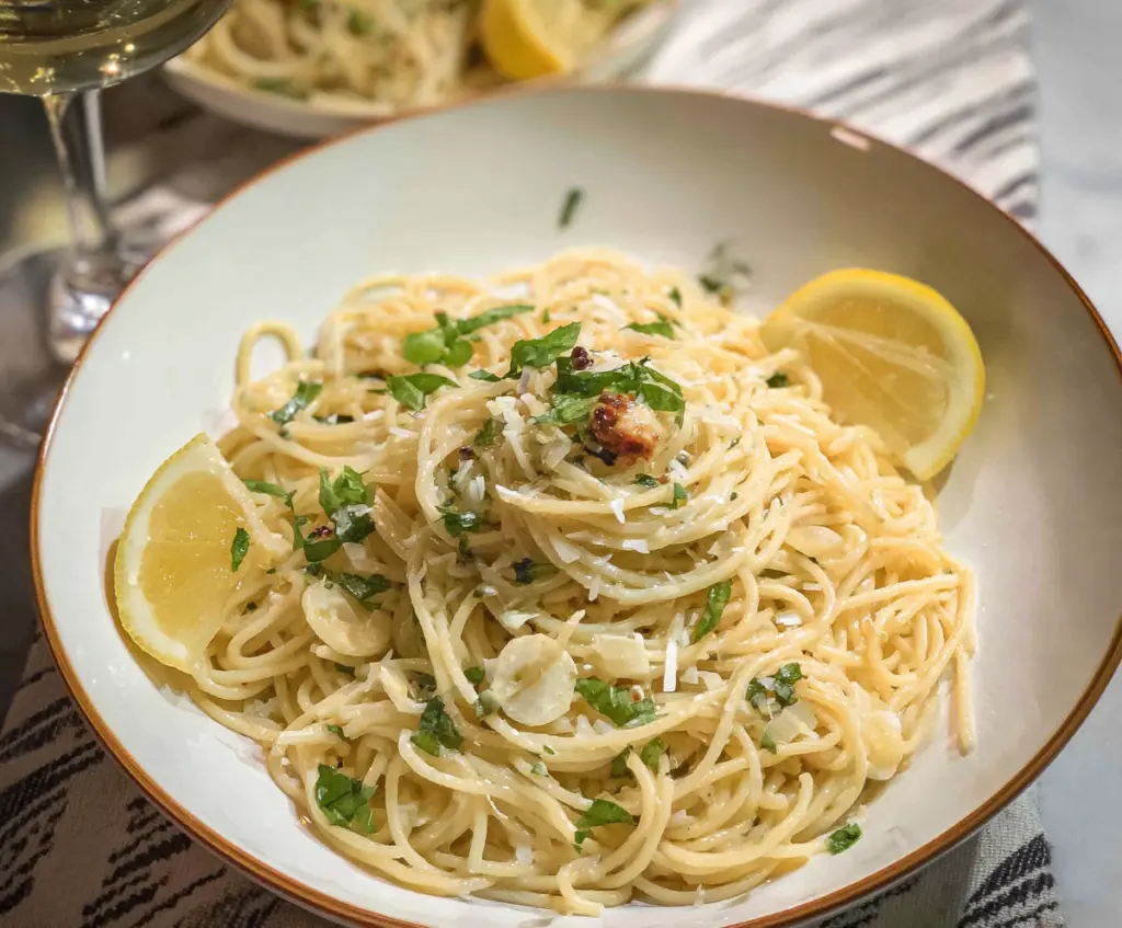 Creamy lemon butter garlic pasta served in a white bowl, garnished with fresh herbs.