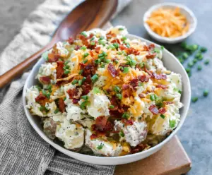 Delicious loaded potato salad with bacon, cheese, and green onions on a serving platter.
